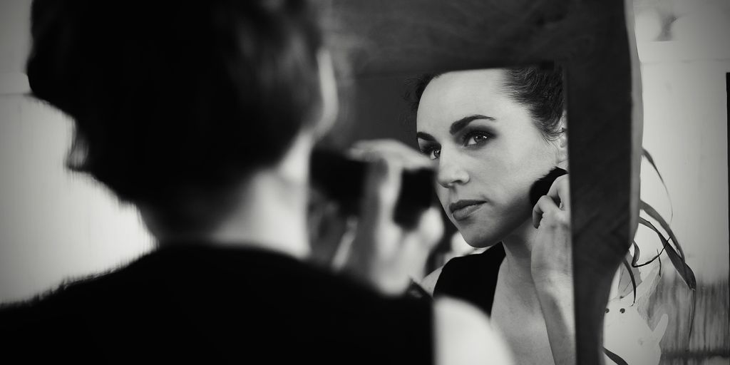 a woman is looking in the mirror while brushing her teeth