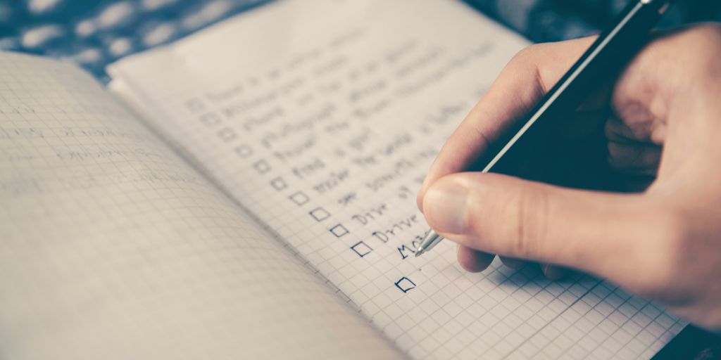 person writing bucket list on book