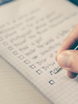 person writing bucket list on book